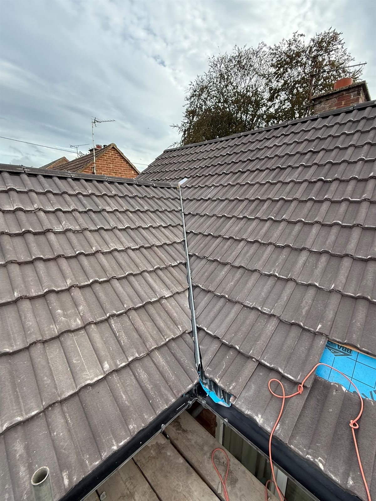 A new grey tiled roof with a lead valley by Top Level Roofing & Building Solutions