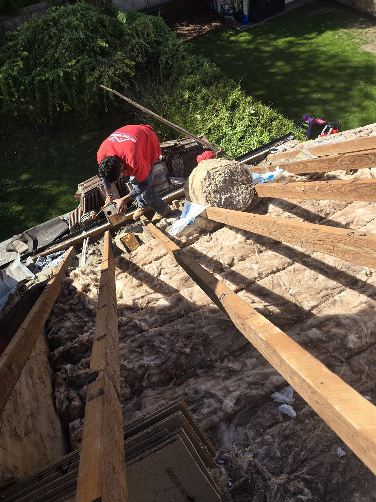 A Top Level Roofing roofer on a roof stripped to the timbers